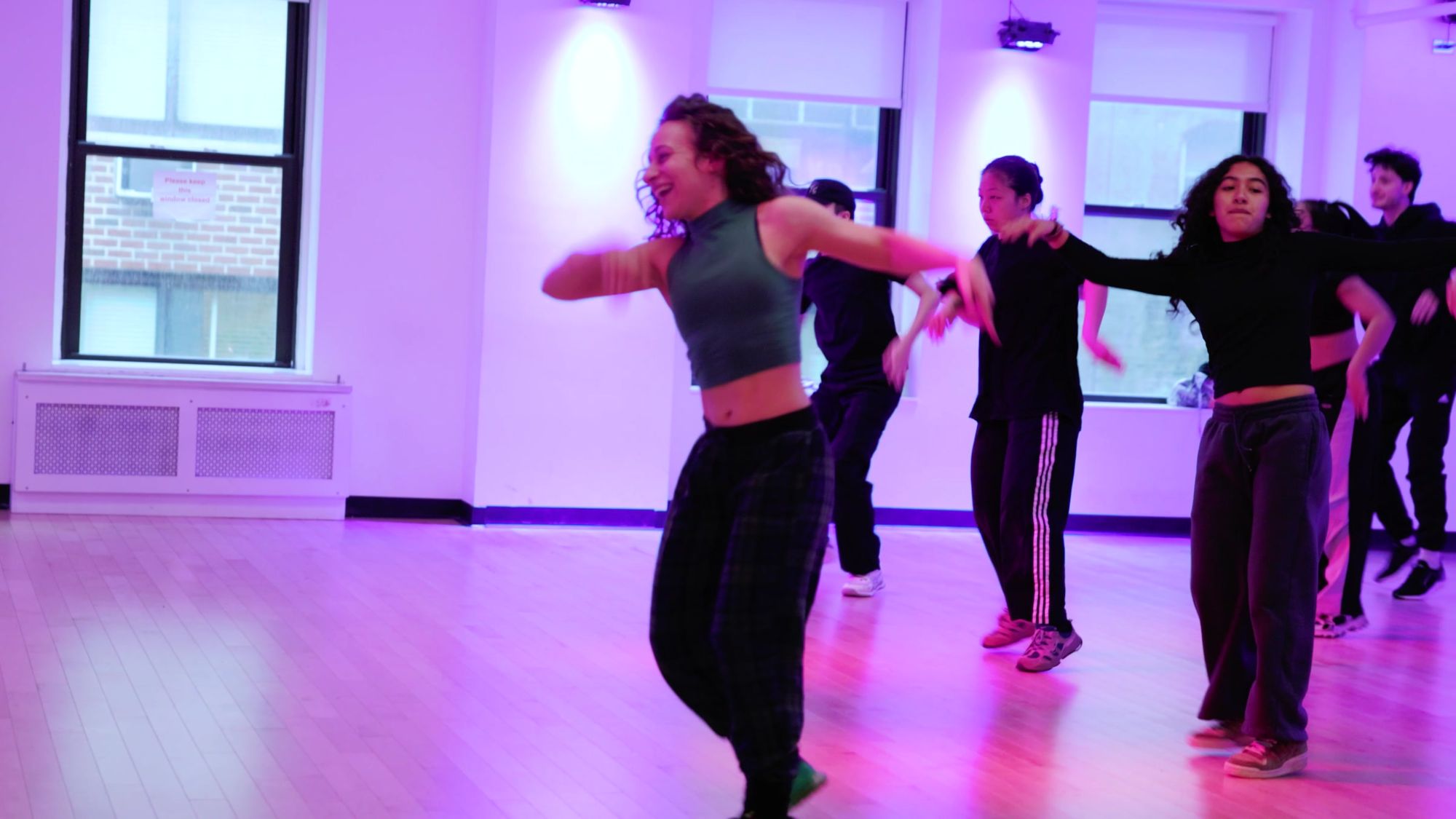 Galit Friedlander teaching a full room at Broadway Dance Center under magenta stage light